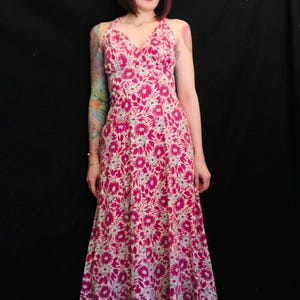 May include: A long, pink and white floral print maxi dress with a halter neckline. The dress has a fitted bodice and a flowing skirt.