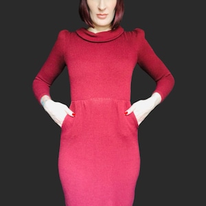 Peut inclure: Une robe longue en tricot rouge avec un col roulé et des poches. La robe a une silhouette ajustée et est faite d'un tissu doux et texturé.