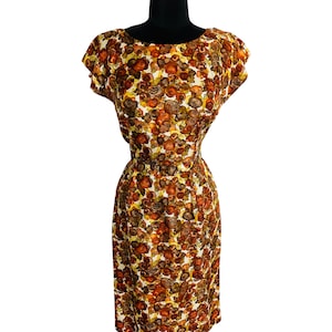 May include: A vintage dress with a brown, orange, and yellow floral print. The dress has a fitted bodice and a slightly flared skirt. It has a round neckline and short sleeves.