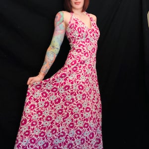 May include: A pink and white floral maxi dress with a halter neckline. The dress has a fitted bodice and a flowing skirt.