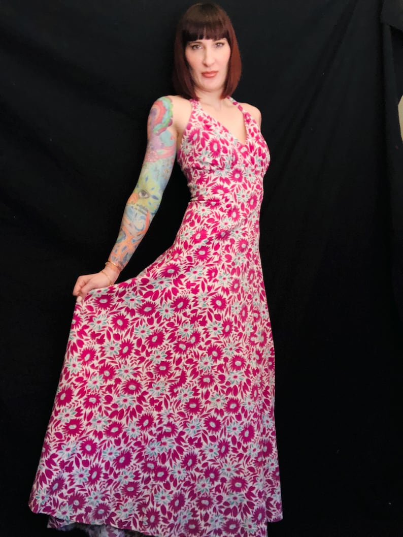 May include: A pink and white floral maxi dress with a halter neckline. The dress has a fitted bodice and a flowing skirt.