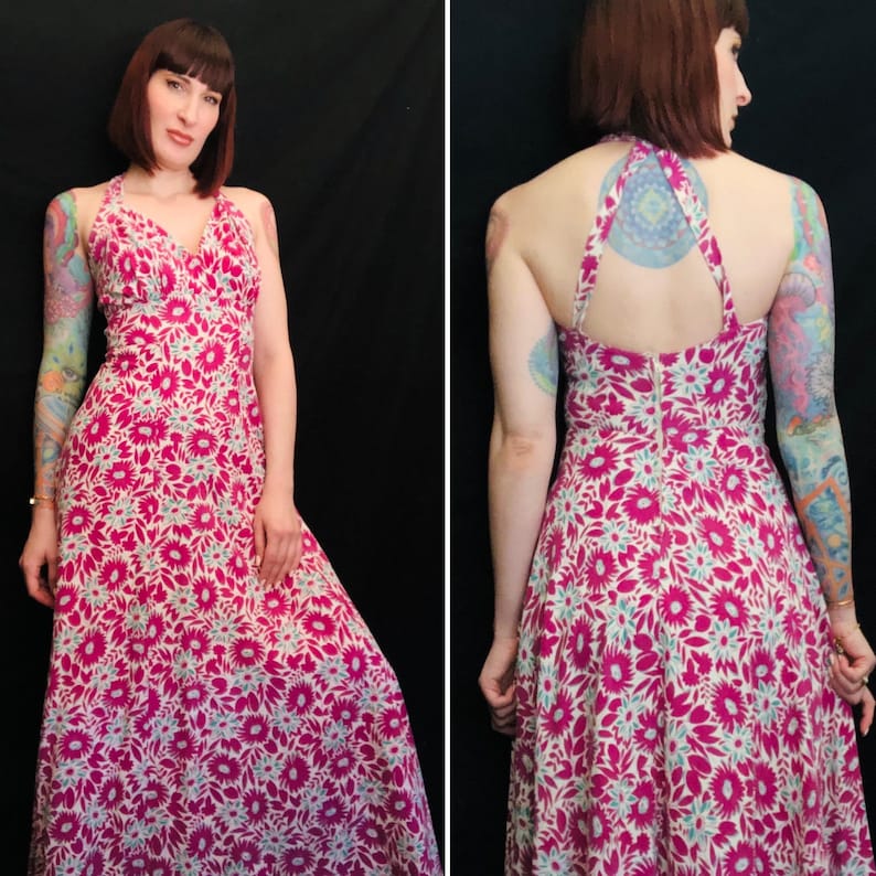 May include: A pink and white floral maxi dress with a halter neckline and a low back. The dress has a fitted bodice and a flowing skirt.