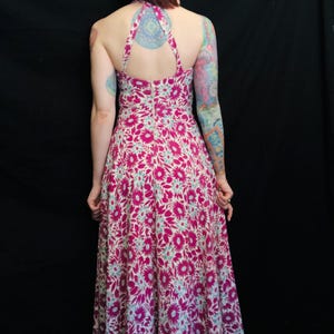 May include: A long, pink and white floral print maxi dress with a halter neckline and a low back.