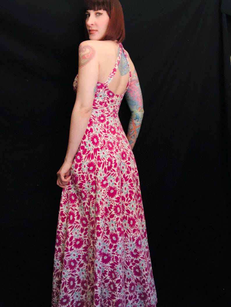 May include: A pink and white floral maxi dress with a halter neckline and a fitted bodice. The dress has a flowing skirt and is made of a lightweight fabric.