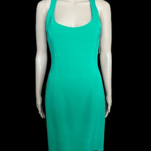 May include: A vibrant emerald green sleeveless dress featuring a scoop neckline and a racerback-style design. The garment has a fitted silhouette with vertical seam detailing running down the front, ending at a knee-length hemline.