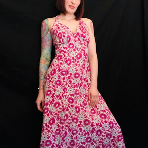 May include: A long pink and white floral print maxi dress with a halter neckline.