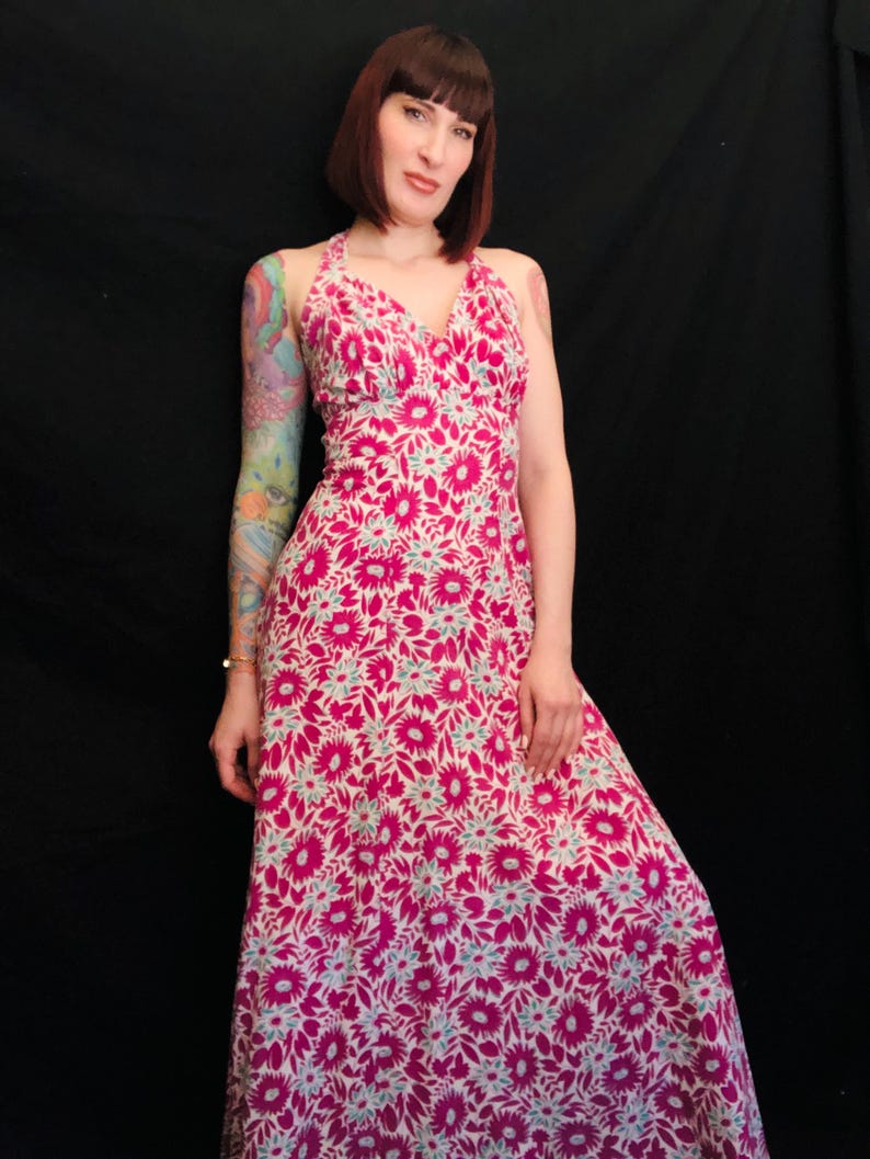 May include: A long pink and white floral print maxi dress with a halter neckline.