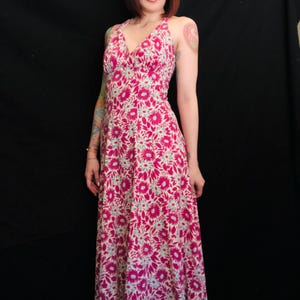 May include: A long pink and white floral print maxi dress with a halter neckline and a V-shaped bodice.