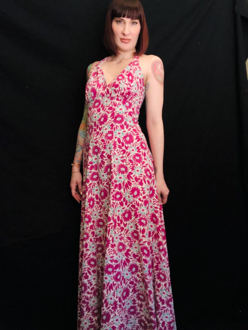 May include: A long pink and white floral print maxi dress with a halter neckline and a V-shaped bodice.