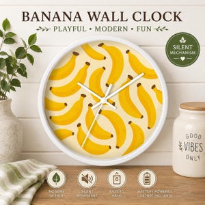 May include: A white-framed wall clock with a yellow banana pattern on the face. The clock has white hands and the text "BANANA WALL CLOCK" at the top. Additional text includes "PLAYFUL • MODERN • FUN" and "SILENT MECHANISM".