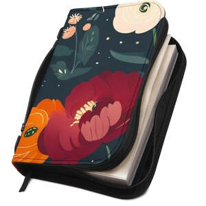 May include: A zippered book cover featuring a floral design with large red and orange flowers, white accents, and green leaves against a dark blue background. The cover is open, revealing a stack of white pages. A black ribbon bookmark is visible.