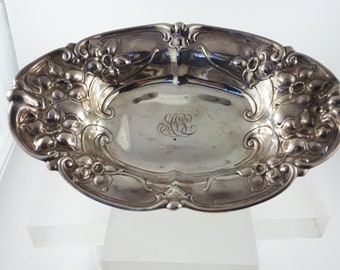 May include: A silver oval dish with a floral design and an engraved monogram. The dish is made of sterling silver and has a polished finish.