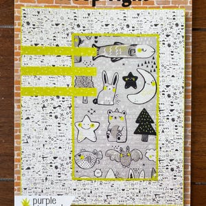 May include: A quilt pattern featuring a gray background with black and white illustrations of animals, stars, and trees. The pattern is framed with a yellow border and the text "Sleep Tight" is printed at the top. The text "Purple Pineapple Studio" and the number "#1704" are printed at the bottom.
