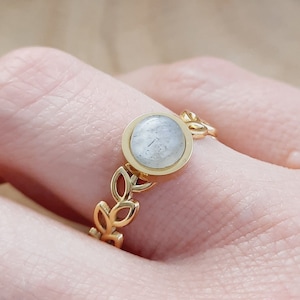May include: A gold ring with a white stone set in a leaf design.