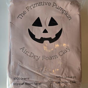 May include: A package of pink air dry foam clay from The Primitive Pumpkin. The package features a jack-o'-lantern face and the text "Air Dry Foam Clay". It weighs 1000 grams and is soft and lightweight.