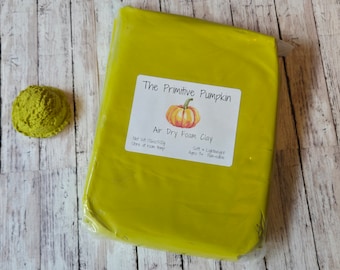 May include: A package of bright yellow air dry foam clay from The Primitive Pumpkin, with a small, textured, green clay creation to the left. The label reads "Air Dry Foam Clay" and "Net Wt 17.6oz/500g".