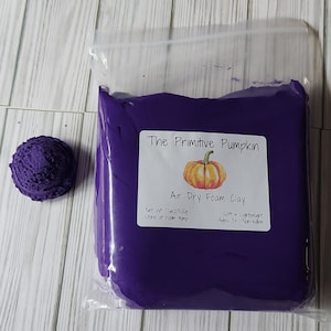 May include: A purple bag of air dry foam clay with a label that reads "The Primitive Pumpkin Air Dry Foam Clay" with a pumpkin illustration. The label also states "Net Wt 17.6oz/500g Store at room temp Soft + Lightweight Ages 3+ Non-edible".