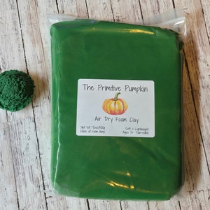 May include: A green bag of air dry foam clay with a label that reads "The Primitive Pumpkin Air Dry Foam Clay" with a drawing of a pumpkin. The label also says "Net Wt 11oz/300g Store at room temp Soft Lightweight Ages 3+ Non-edible".