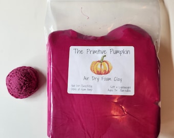 Puede incluir: Una bolsa de arcilla de espuma de secado al aire de color rosa con una etiqueta que dice "The Primitive Pumpkin Air Dry Foam Clay" con una pequeña ilustración de calabaza. La etiqueta también dice "Net Wt 17.6oz/500g Store at room temp Soft + Lightweight Ages 3+ Non-edible".