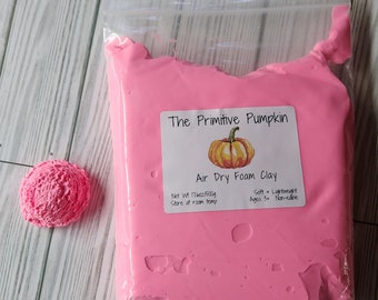 Puede incluir: Una bolsa rosa de arcilla de espuma de secado al aire con una etiqueta que dice "The Primitive Pumpkin Air Dry Foam Clay Net Wt 11.6oz/500g Soft & Lightweight Store at room temp Ages 3+ Non-edible"
