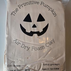 May include: A package of air dry foam clay from "The Primitive Pumpkin." The package features a jack-o'-lantern face and text that reads "Air Dry Foam Clay." The package contains 1000 grams of clay and is suitable for ages 3 and up.