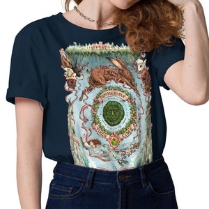 May include: Navy blue t-shirt featuring a detailed illustration with the text "Summer Rise". The design includes a central green face surrounded by a wreath, a rabbit, and other whimsical elements. The shirt is made of a soft material.