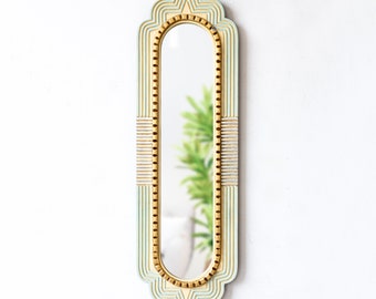 May include: A tall, rectangular mirror with a decorative frame. The frame is made of wood and painted in a light blue color with gold accents. The mirror has a rounded top and bottom.