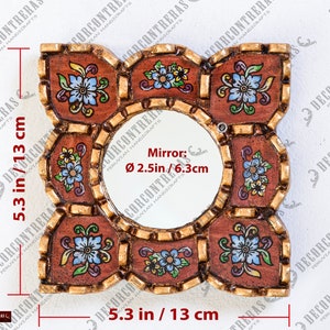 May include: Square decorative mirror, 5.3 inches (13 cm) wide and tall, with a central round mirror, 2.5 inches (6.3 cm) in diameter. The frame is brown with gold accents and floral designs in blue, yellow, and white.