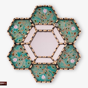 May include: A hexagonal mirror with a teal and gold frame. The frame is made of individual hexagonal tiles with a floral design. The mirror is surrounded by a gold border.