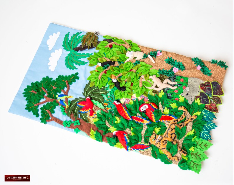 May include: A felt wall hanging depicting a jungle scene with green trees, red parrots, monkeys, and a tiger. The scene is made of felt and sewn together.
