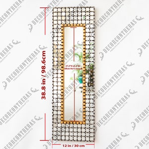 May include: A rectangular mirror with a gold and silver mosaic frame. The mirror is 38.8 inches tall and 12 inches wide. The frame is made of small squares of gold and silver metal.