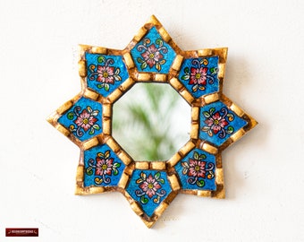 May include: A small, octagonal mirror with a blue and gold frame. The frame is decorated with intricate floral designs in shades of pink, green, and gold. The mirror is perfect for adding a touch of elegance to any room.