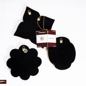 Puede incluir: Tres piezas de decoraci&oacute;n de pared negras con detalles dorados. Cada pieza tiene una forma diferente, incluyendo una flor, una estrella y una forma redondeada. Las piezas tienen un gancho para colgar en la parte posterior.