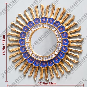 May include: A gold sunburst mirror with a blue and white tiled frame. The mirror is 17.7 inches in diameter.