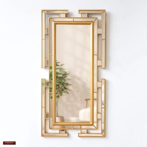 May include: A gold-toned rectangular mirror with a geometric frame. The mirror has a simple design with a clean, modern look.