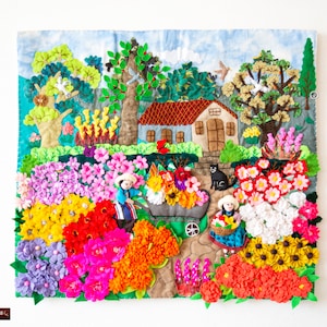 May include: A detailed textile artwork showing a garden scene with a house, trees, and figures. The piece uses various textures and colours to depict flowers, a wheelbarrow, and a black cat. The overall design creates a charming and detailed landscape, suitable for wall decor.