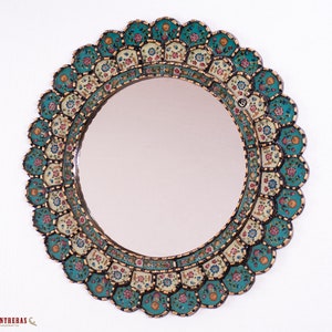 May include: A round wall mirror featuring a decorative frame with a scalloped edge. The frame is adorned with a repeating pattern of turquoise and cream-colored segments, each decorated with small, colorful floral motifs and gold-toned outlines.