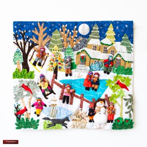 Puede incluir: Un tapiz de pared de fieltro de colores que representa una escena de invierno con una casa, un lago helado, un árbol de Navidad y personas disfrutando de actividades invernales. La escena se desarrolla sobre un fondo de cielo nocturno azul con estrellas y luna llena.