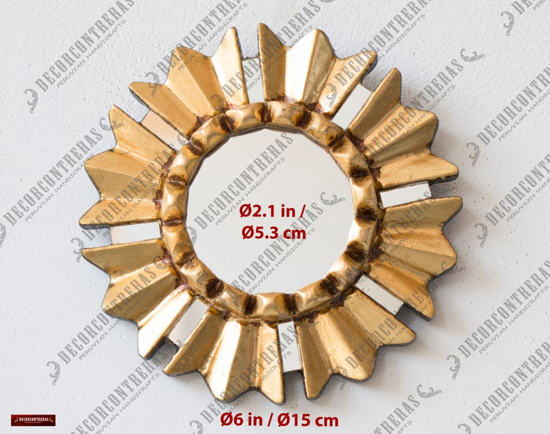 May include: A gold-coloured sunburst mirror with a central circular mirror. The frame features a textured, radiating design. The overall diameter is 15 cm, and the central mirror is 5.3 cm in diameter.