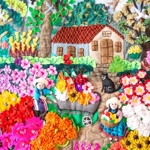 May include: A detailed textile artwork showing a garden scene with a house, trees, flowers, and figures. The piece features a variety of vibrant flowers in shades of pink, red, orange, and yellow. A black cat is near the house.