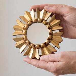 Gold Small Mirror 6", hand-carved Peruvian bronze leaf art by UNESCO artist Edmundo Contreras. Features a sunburst-style frame with hand-cut mirror mosaic pieces on the border. Antique-style round decorative mirror for gallery walls. Handcrafted in Peru, ships locally within USA