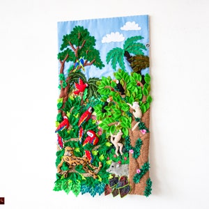 May include: A colorful felt wall hanging depicting a jungle scene with parrots, monkeys, a jaguar, and a toucan. The background is a blue sky with white clouds.
