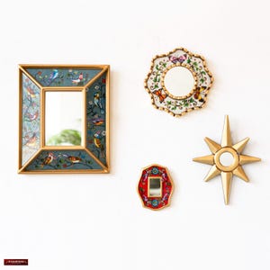 May include: Four decorative mirrors with gold frames and colorful designs. The largest mirror has a blue background with birds and flowers. The second largest mirror has a red background with flowers. The smallest mirror has a gold star shape. The fourth mirror has a gold frame with butterflies and flowers.