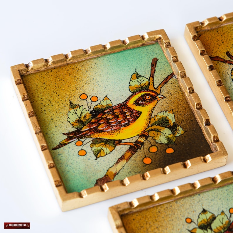 May include: Set of four square coasters with a gold frame. Each coaster features a hand-painted image of a yellow bird perched on a branch with green leaves and orange berries.