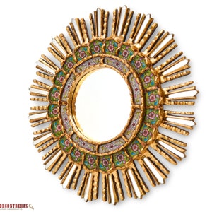 May include: A gold sunburst mirror with a round, mirrored center and a decorative border of green, pink, and white floral designs.