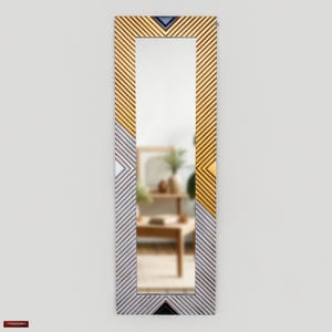 May include: A tall, rectangular mirror with a white and gold geometric pattern frame. The frame has a chevron design with alternating gold and white stripes.