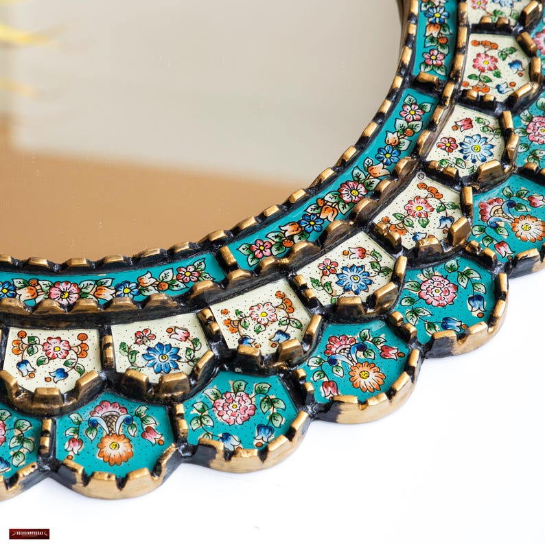 Close detail of the antique gold finish on the scalloped edge of this hand painted Peruvian mirror, showing the metallic worked by hand over a black base beside the layered turquoise brushwork of the colonial floral panels, each one set in its own stepped tier.