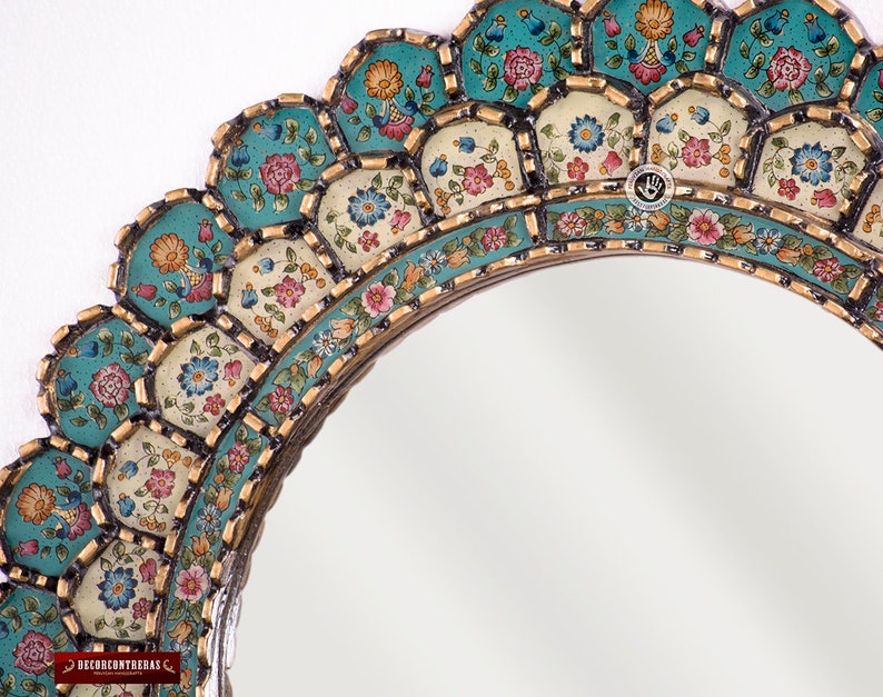 Close detail of the antique gold finish on the scalloped edge of this hand painted Peruvian mirror, showing the metallic worked by hand over a black base beside the layered turquoise brushwork of the colonial floral panels, each one set in its own stepped tier.