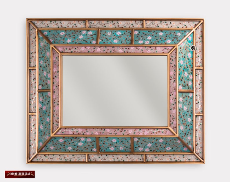 May include: A decorative mirror with a gold frame and a mosaic design. The mosaic features pink and teal tiles with floral patterns.