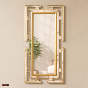 May include: A rectangular wall mirror featuring a gold-toned frame with an intricate, geometric, open-work design. The central glass panel is surrounded by smaller, segmented mirror pieces integrated into the metallic structure, creating a layered, architectural appearance.